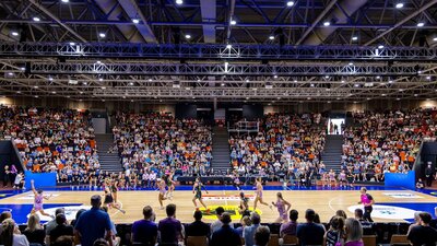 Indoor basketball court with a stadium of spectators.