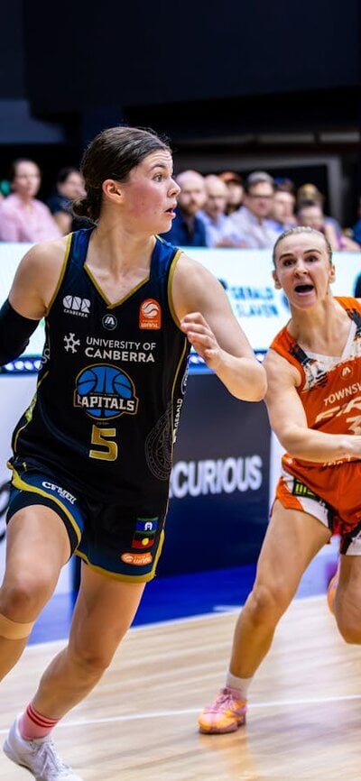 Jade Melbourne Dribbles the ball past Townsville Fire player heading towards the basket, and score..