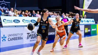 Jade Melbourne Dribbles the ball past Townsville Fire player heading towards the basket, and score..