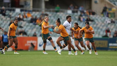 Rugby player running with ball in hand while team mates watch