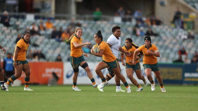 Rugby player running with ball in hand while team mates watch