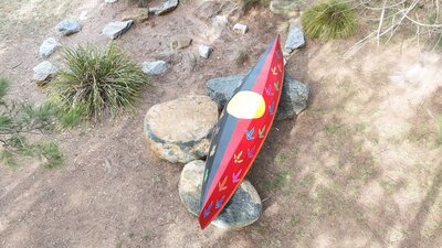 A canoe painted with the Aboriginal flag and multicoloured bird tracks.