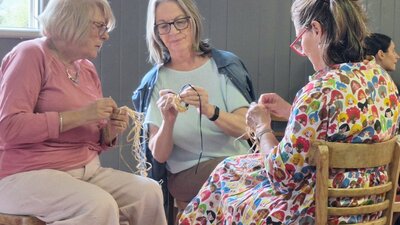 Three ladies talking and weaving with their hands
