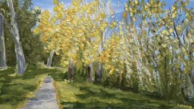 Trees with yellow and green leaves and a path with a blue sky background.