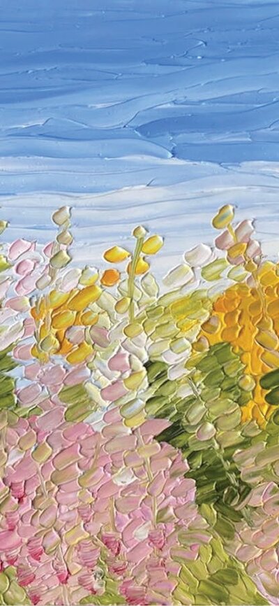 A meadow of pink, white and yellow flowers with a blue sky.