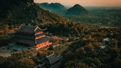 A temple with orange light cast on it in a misty mountainous location